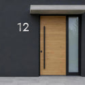 Numéro de maison Claire en inox sur une façade sombre